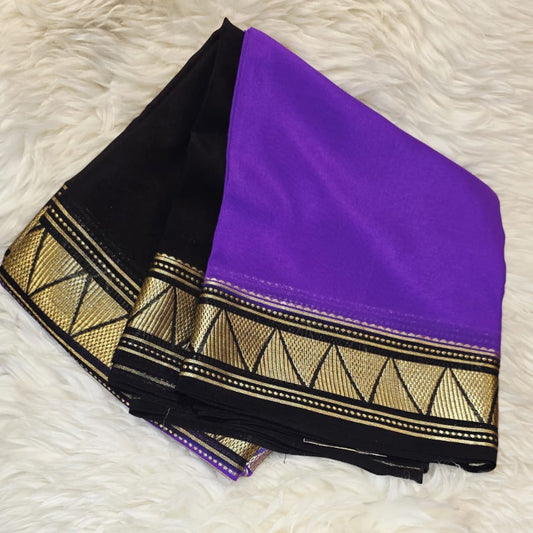 Black saree with purple blouse and gold border on a white textured background
